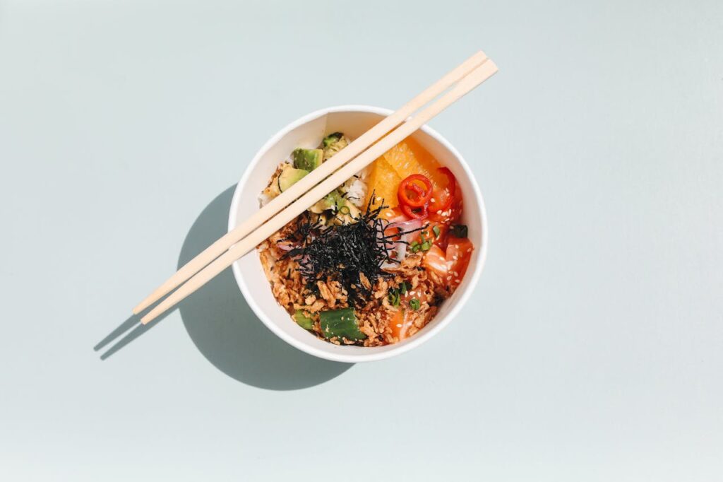 Close-up of a vibrant Hawaiian poke bowl with fresh ingredients and chopsticks. Top view.